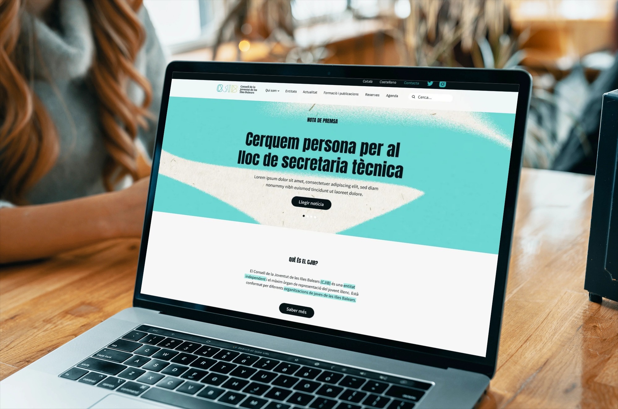 Un ordenador portátil sobre una mesa de madera donde podemos ver la pantalla. En ella se ve el diseño de la página de inicio de la web del Consell de la juventut de les Illes Balears